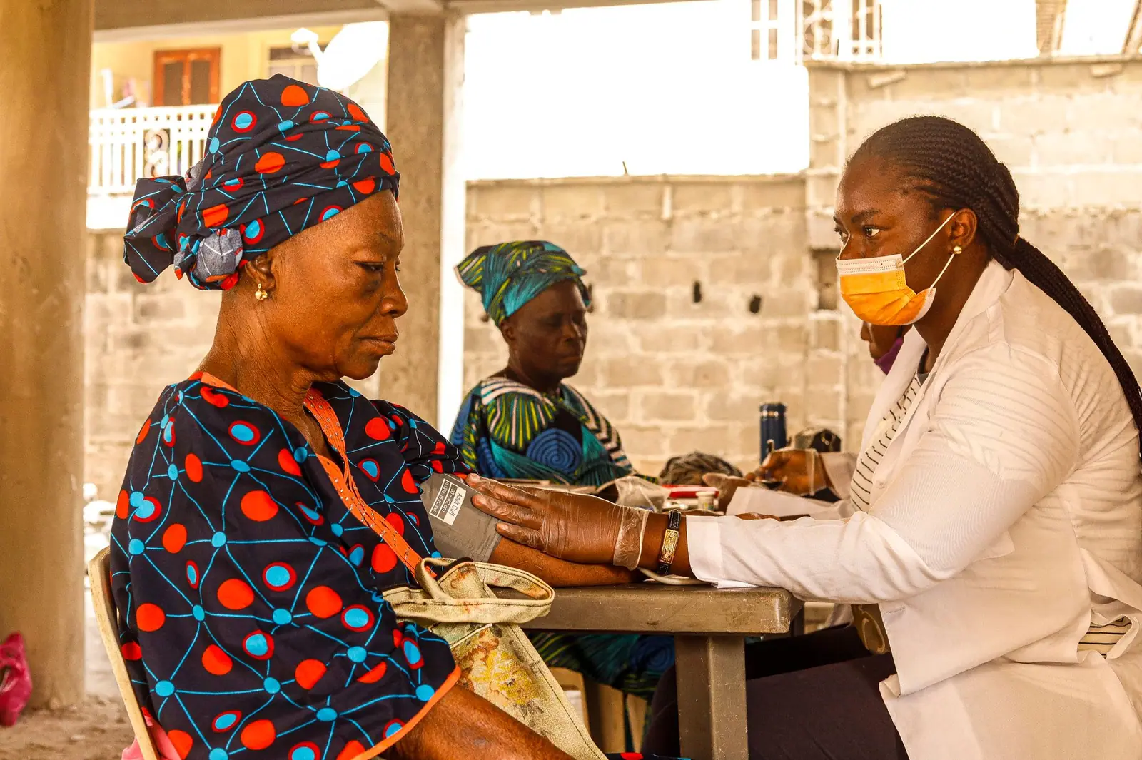 Health worker checking an older woman’s blood pressure at a table