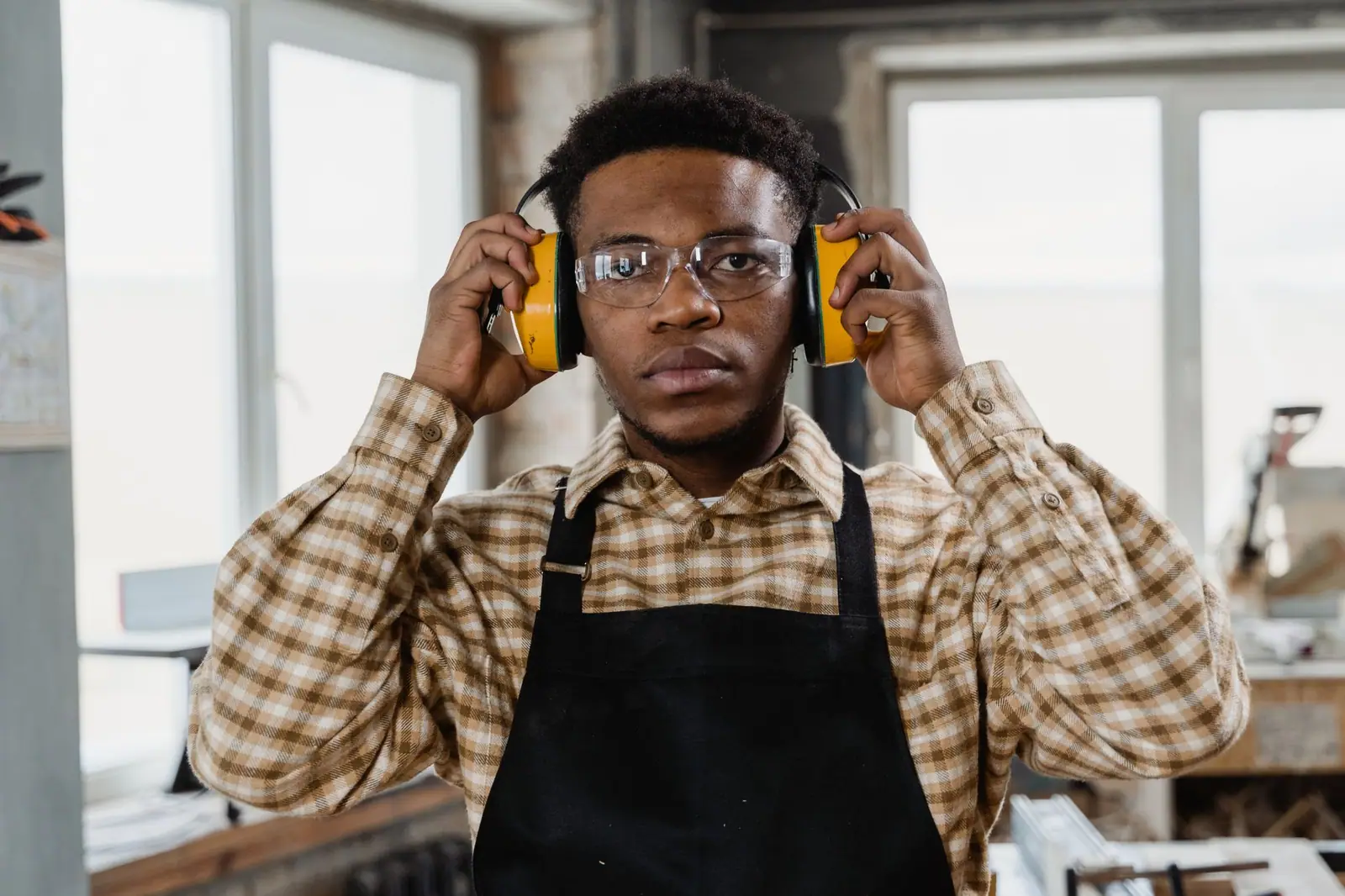 Worker wearing ear defenders to protect his hearing from machine noise