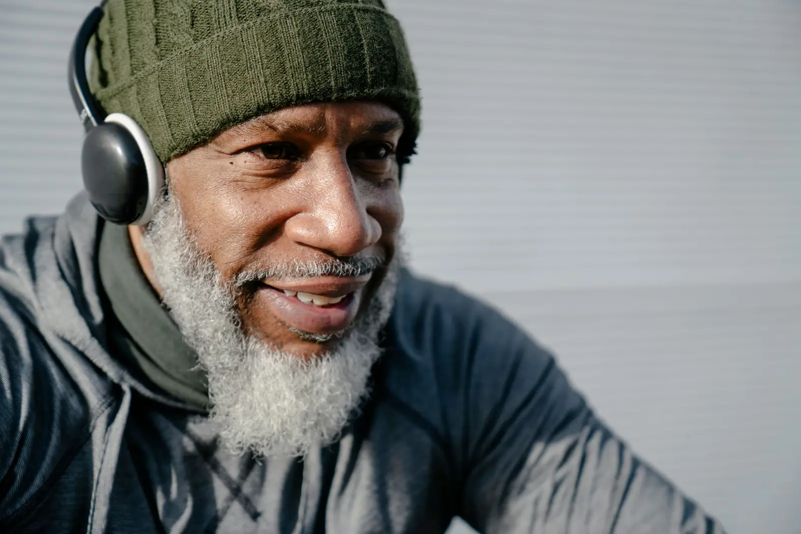 Smiling older man wearing headphones, ready for a hearing test at home